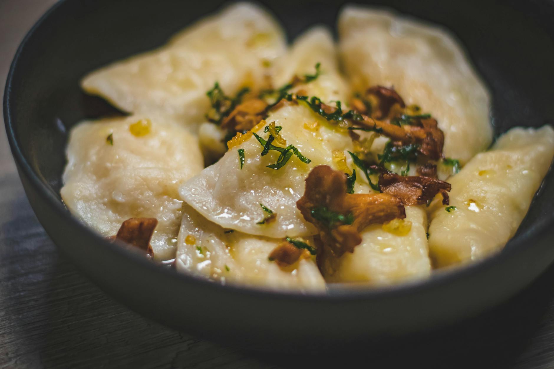 Pierogi z kurkami i ziołami podane na talerzu w domowym wnętrzu